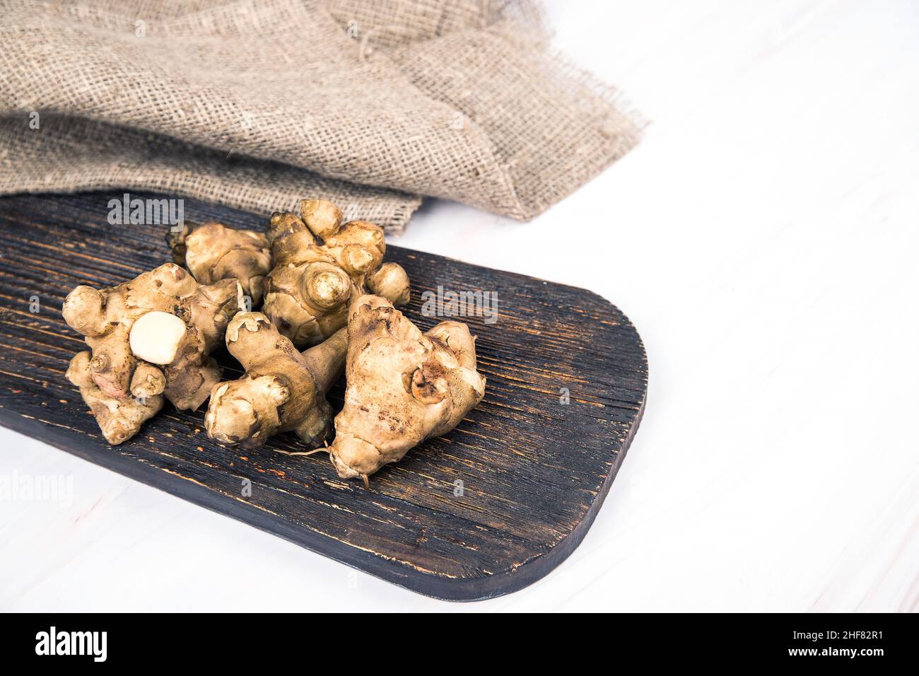 I tuberi di carciofo di Gerusalemme si trovano su una tavola di legno su un tavolo leggero. Spazio copia Foto Stock