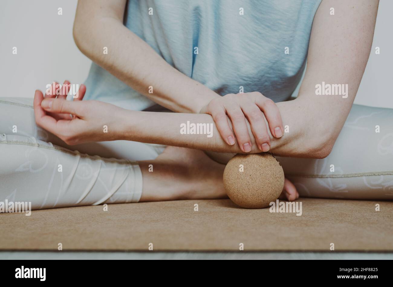Muscoli dell'avambraccio rilascio miofasciale con grande palla da massaggio in sughero su tappeto yoga in sughero. Concetto: Pratiche di cura di sé a casa Foto Stock