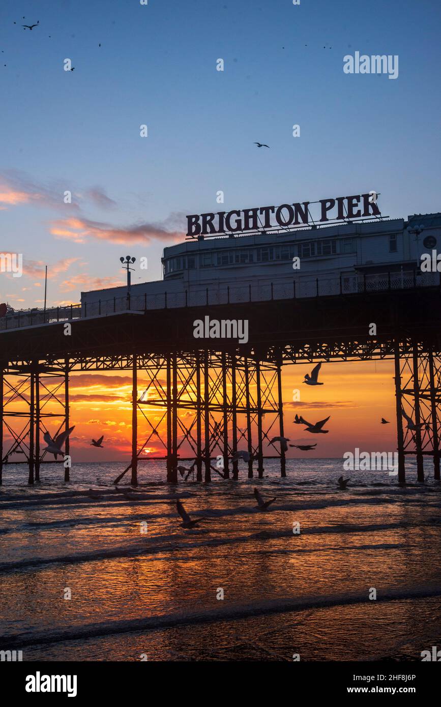 Il sole tramonta dietro il molo di Brighton Foto Stock