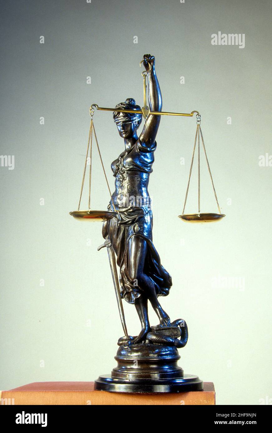 Una statua simbolica in bronzo di una giustizia femminile cieca che porta una spada e tiene le bilance della giustizia. Foto Stock