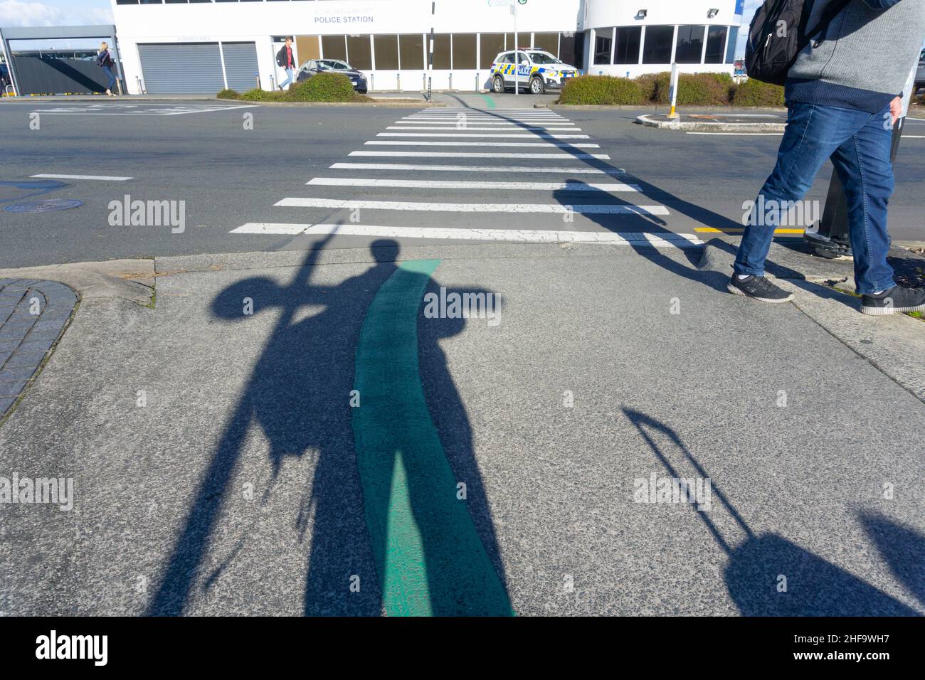 Auckland Nuova Zelanda - Luglio 12 2018; Ombre di viaggiatori, borse e gambe in aeroporto con veicolo di polizia attraverso attraversamento pedonale. Foto Stock