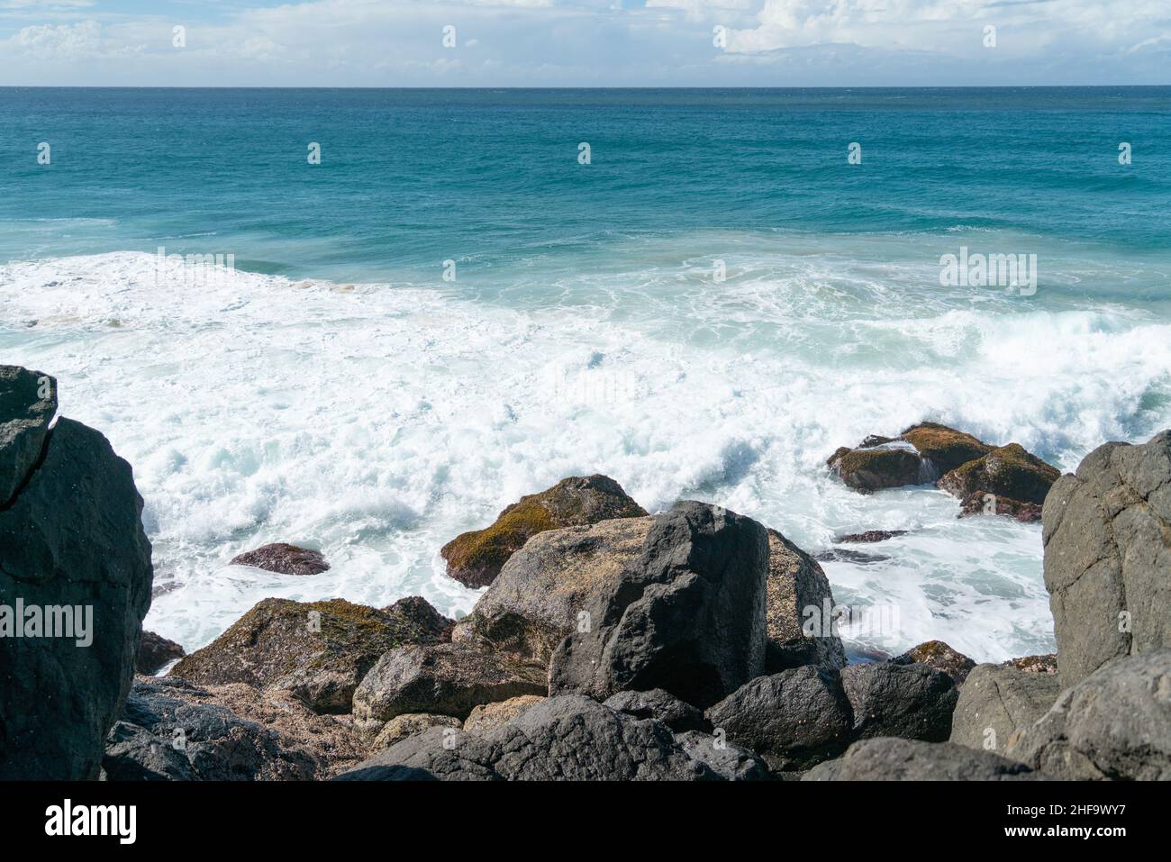 Aspri bordi rocciosi delle acque con il mare che oscura dentro e vista all'orizzonte. Foto Stock