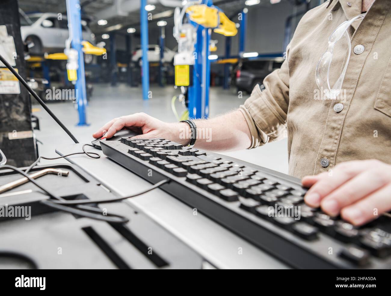 Documentazione del database dei veicoli per il controllo da parte del tecnico automobilistico caucasico. Tastiera del computer all'interno della stazione di servizio automatica. Foto Stock