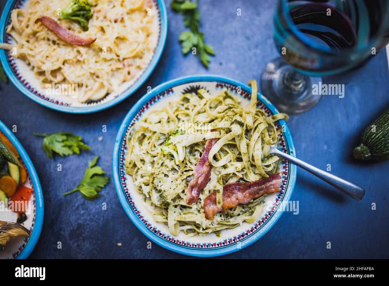Due piatti di pasta deliziosa con strisce di pancetta sopra la superficie scura Foto Stock