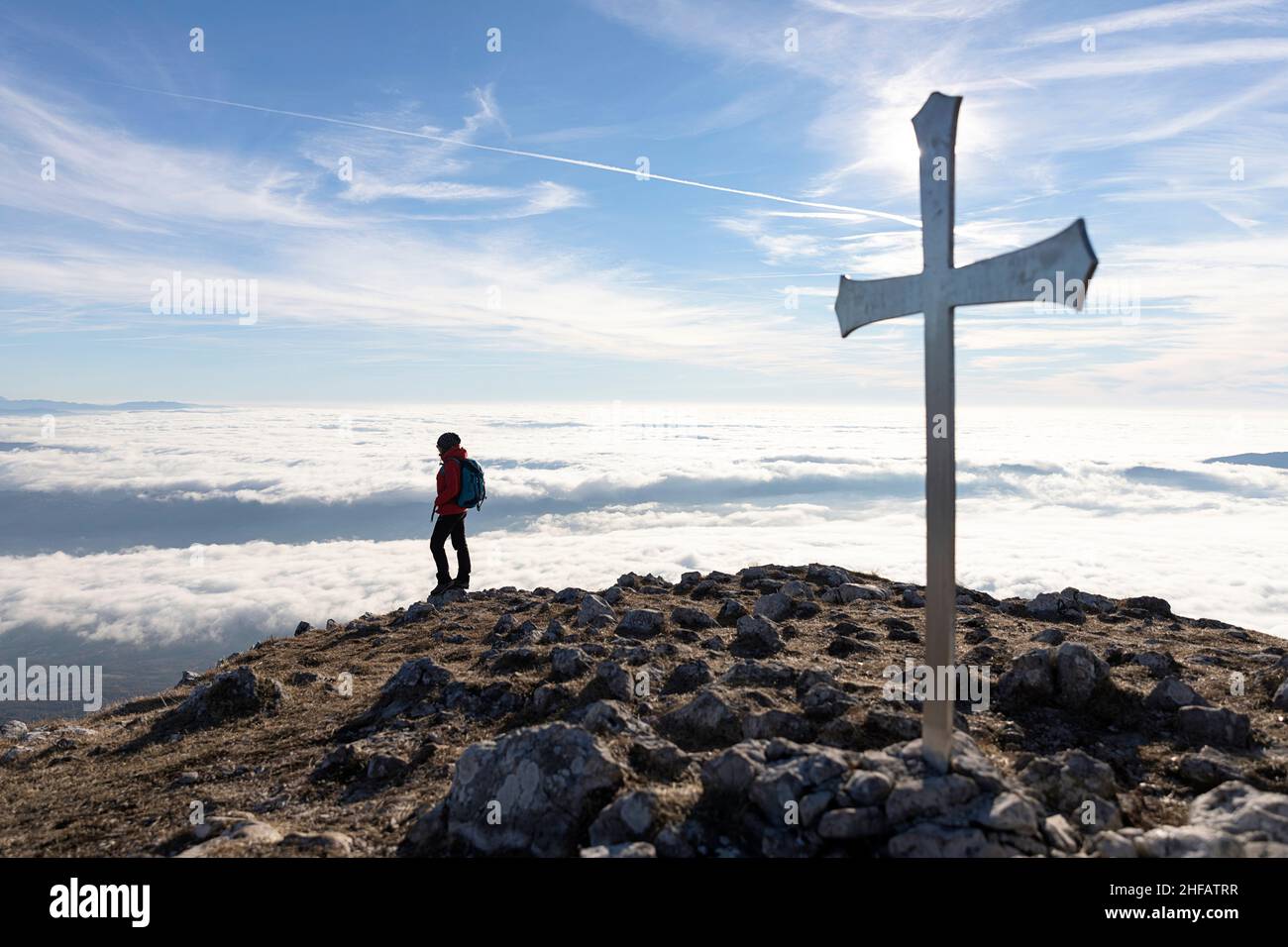 Donna in piedi a croce sulla cima del monte Kucelj, sopra la nebbia nella valle di Vipava, Slovenia Foto Stock