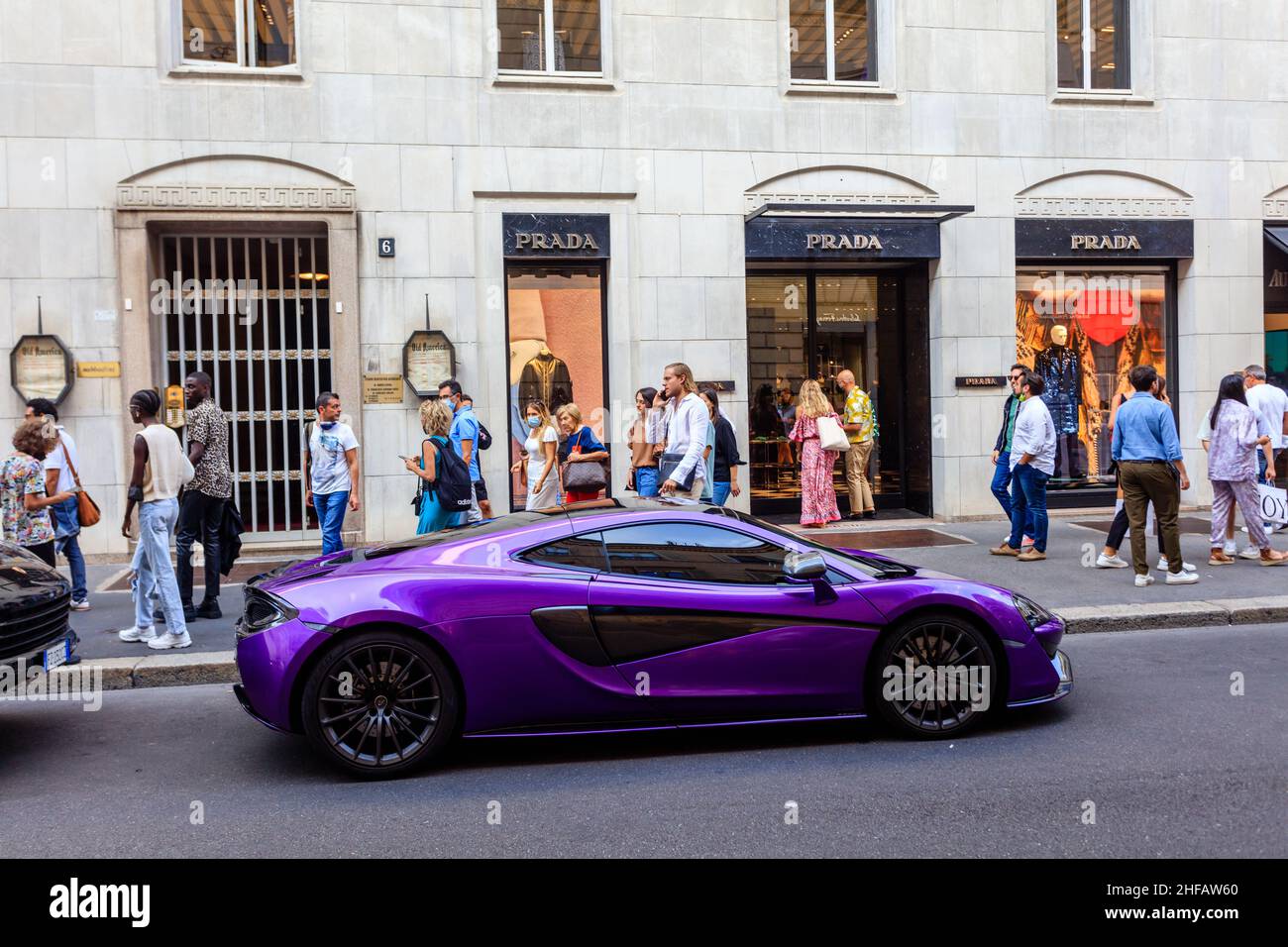 Un'auto sportiva McLaren è parcheggiata accanto ad un negozio Prada nella via della moda Via Monte Napoleone di Milano. Italia. Foto Stock