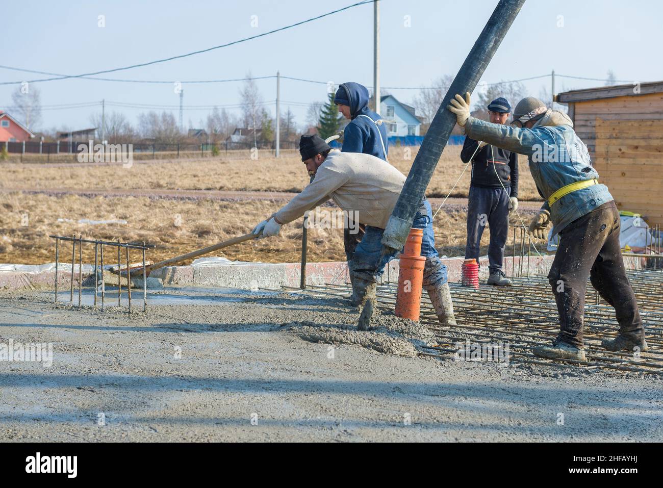 REGIONE DI LENINGRAD, RUSSIA - 28 MARZO 2021: Lavoratori migranti che versano nella fondazione di una casa di campagna in costruzione Foto Stock