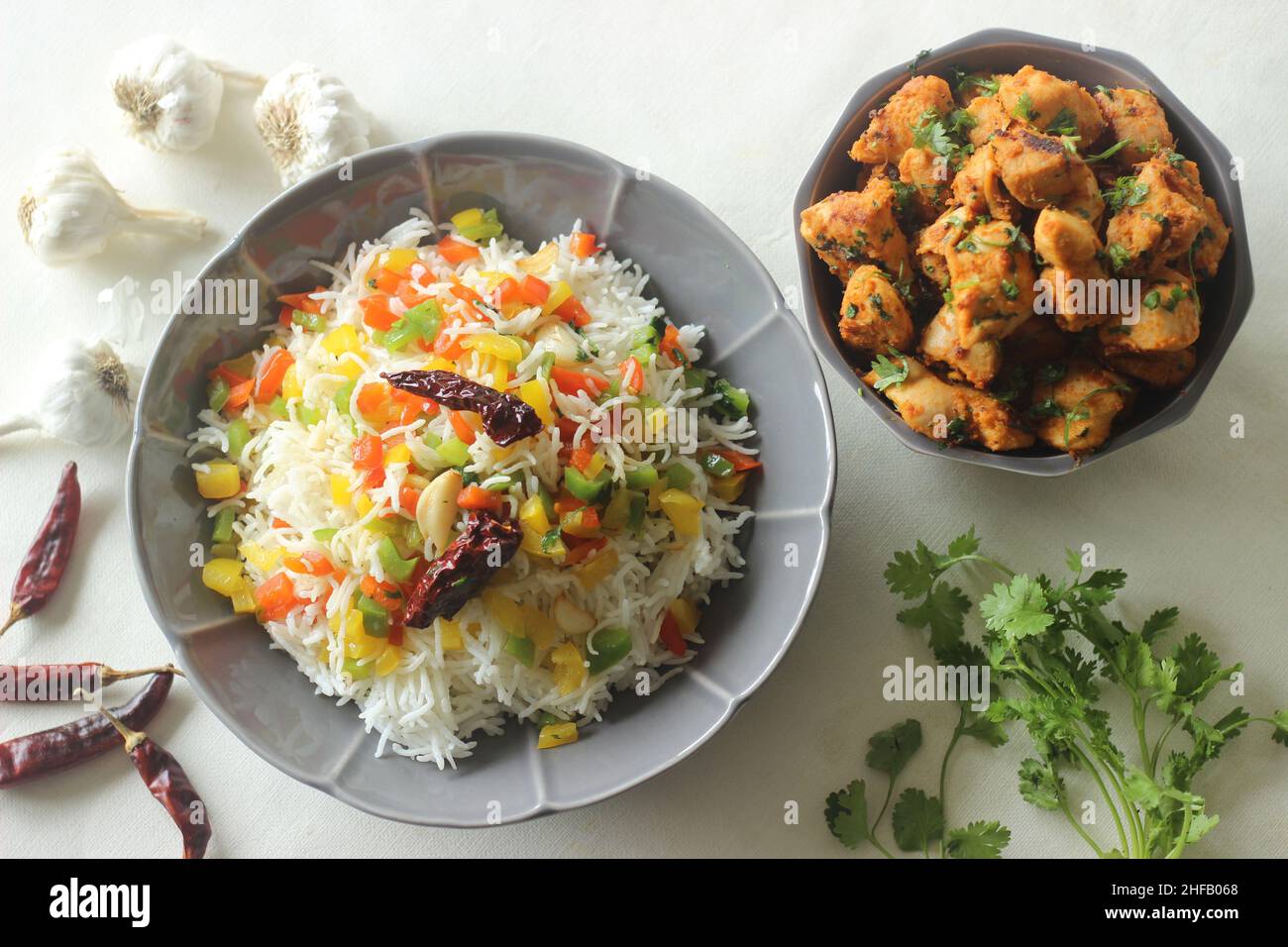 Riso basmati al vapore con peperoni saltati aromatizzati con peperoni rossi e aglio. Servito con piti di pollo all'aglio peperoncino in una ciotola. Scatto Foto Stock