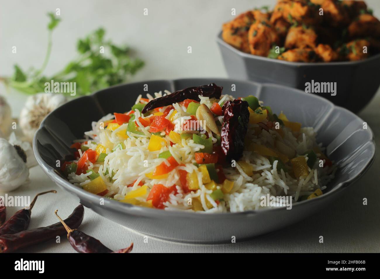 Riso basmati al vapore con peperoni saltati aromatizzati con peperoni rossi e aglio. Servito con piti di pollo all'aglio peperoncino in una ciotola. Scatto Foto Stock