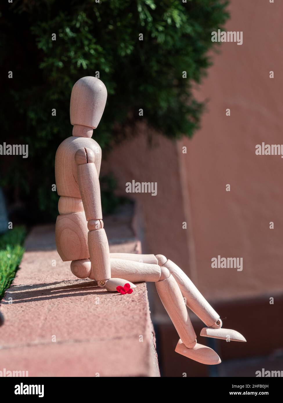 Bambola di legno umana seduta sul pavimento Foto Stock