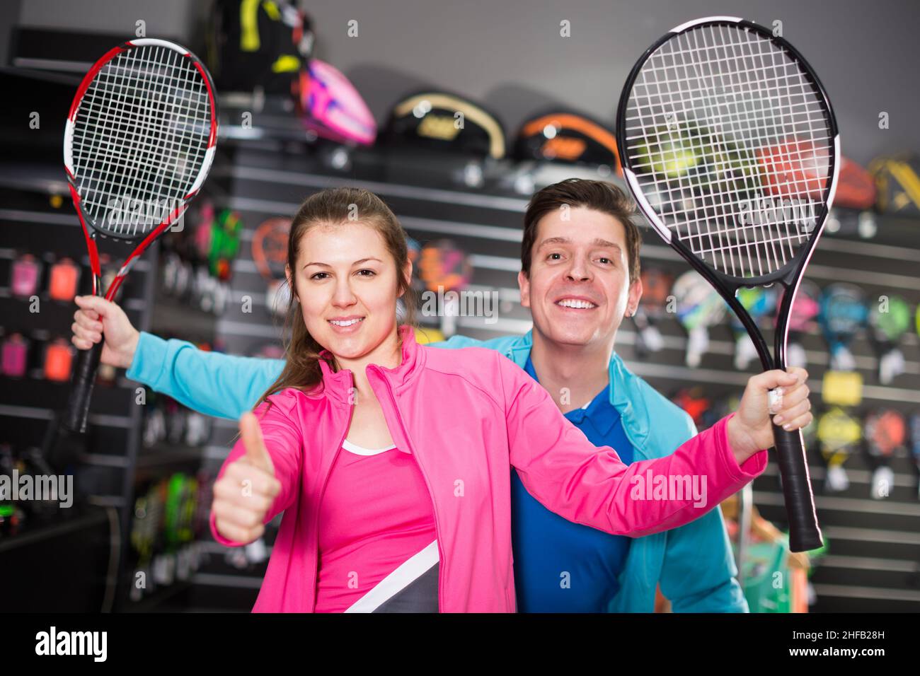 La coppia sportiva in uniforme sta dimostrando nel negozio un nuovo razzo per il tennis Foto Stock