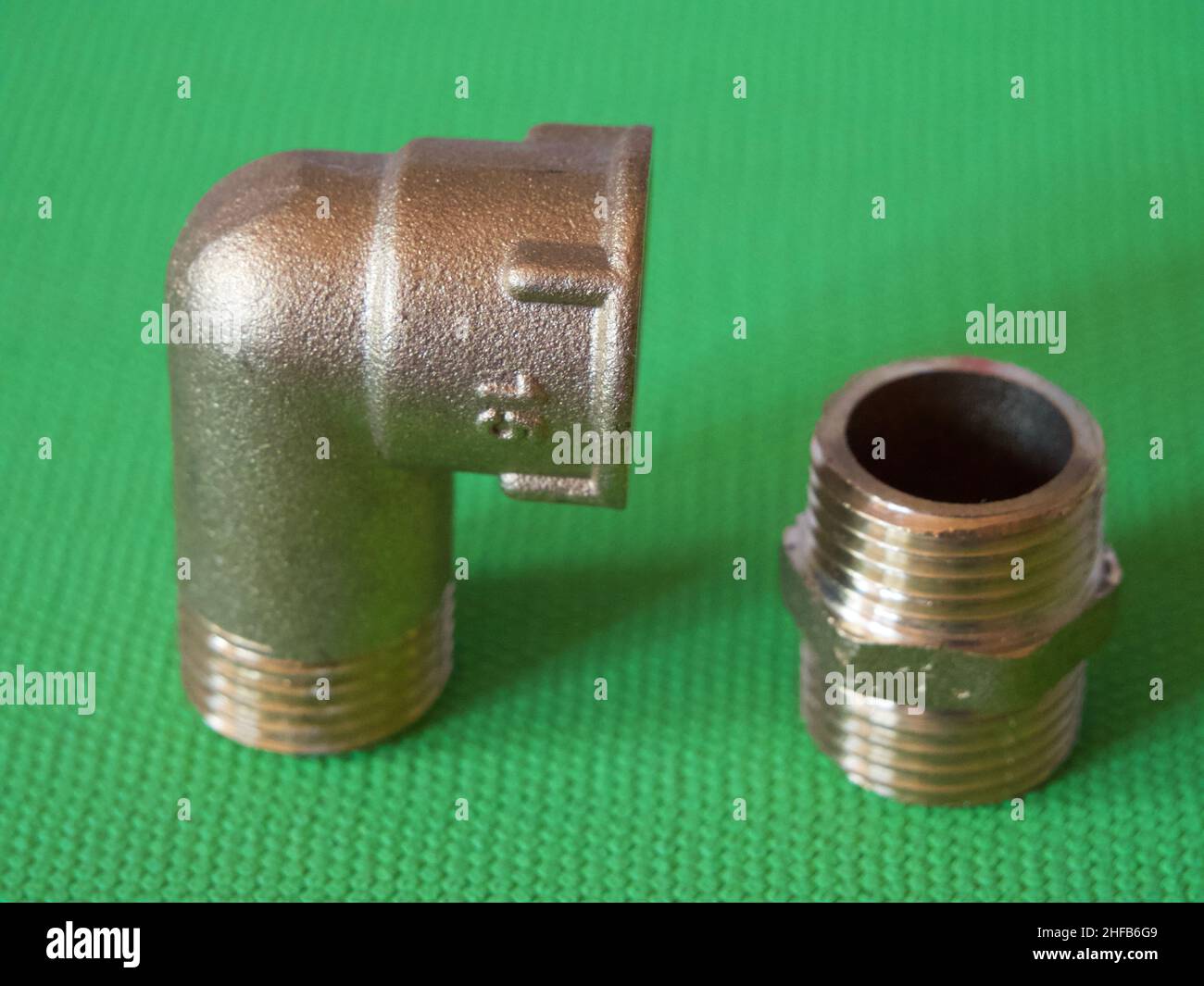 Gomito adattatore in ottone con filettatura interna-esterna e nipplo in ottone, utilizzato per collegare tubi con raccordi filettati dello stesso diametro. Foto Stock