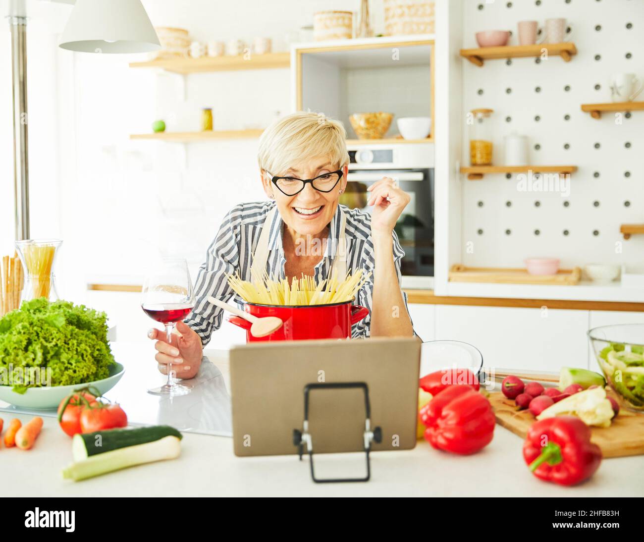Ritratto di una donna anziana felice che guarda il tablet per istruzioni ricetta in cucina Foto Stock