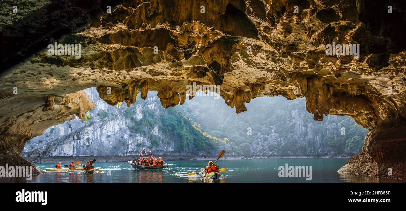 Eine Gruppe von Touristen paddelt in Kajaks in einer Felsenhöhle in der Halong-Bucht Foto Stock