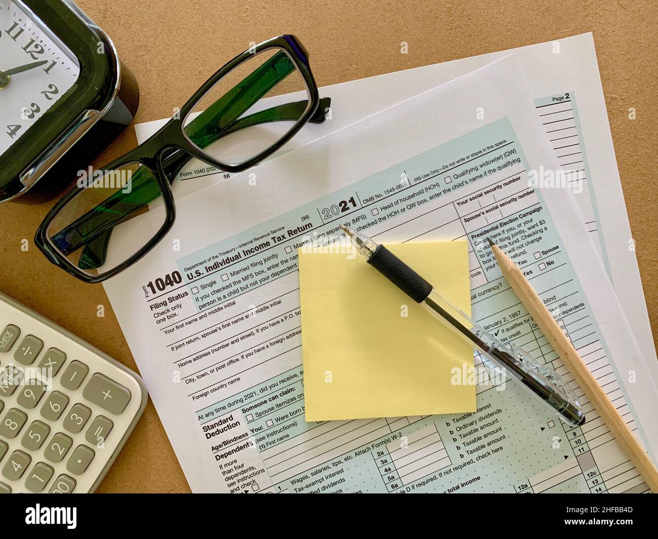 1040 US forma fiscale individuale con adesivi, penna, matita, calcolatrice, occhiali e orologio nero. Foto Stock