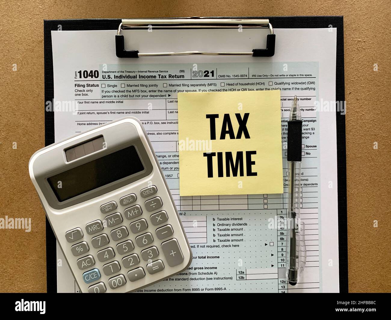 1040 modulo fiscale individuale USA, calcolatrice, penna e testo dell'ora fiscale su adesivo giallo. Concetto di imposta. Foto Stock