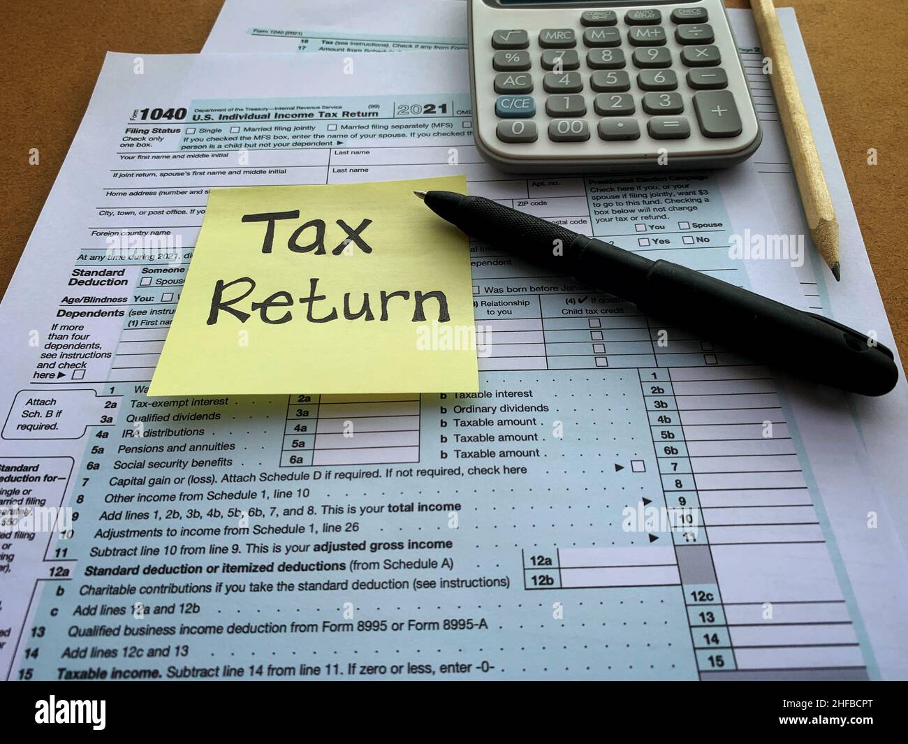 Primo piano sulla dichiarazione delle imposte sulla nota adesiva con modulo delle imposte 1040, penna e calcolatrice. Concetto di tassazione. Foto Stock