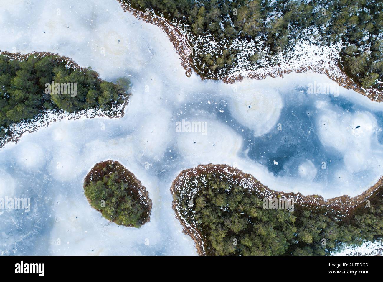 Una splendida vista aerea di un lago di palude ghiacciata con una piccola isola nella natura selvaggia dell'Estonia. Foto Stock