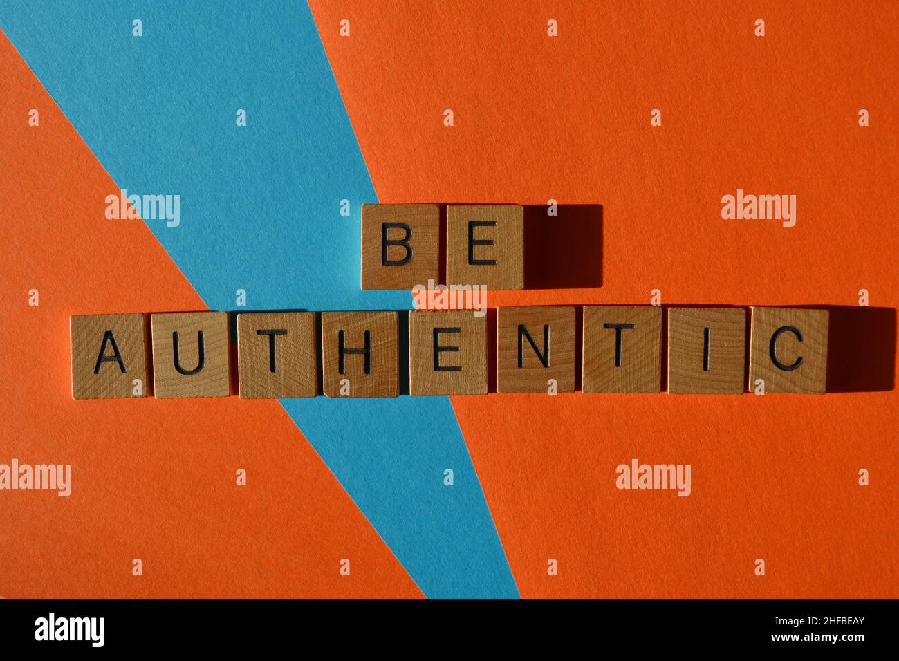Essere autentici, parole in lettere di legno lettera isolata su sfondo arancione e blu Foto Stock