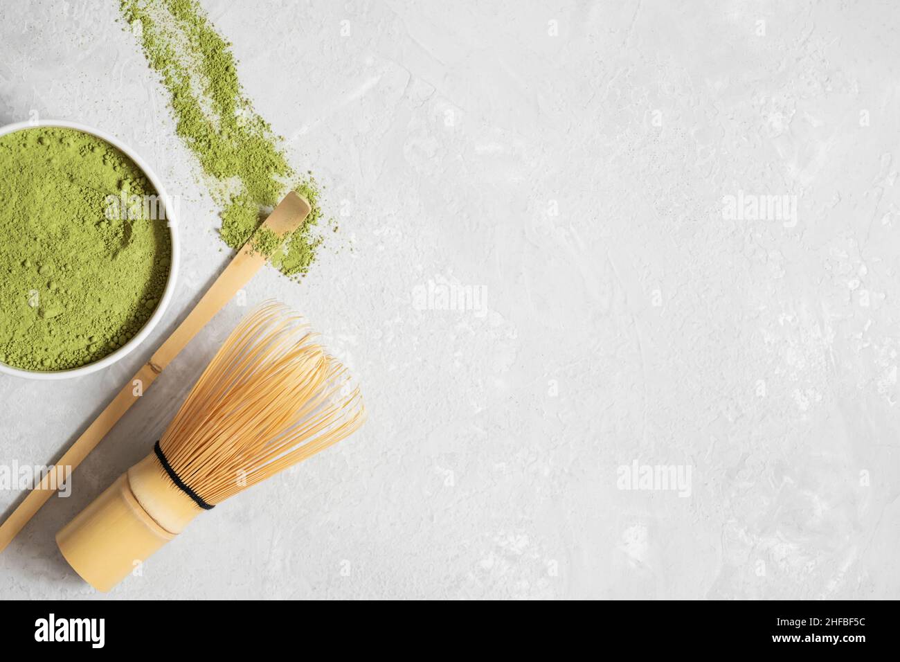 Polvere di tè verde Matcha, whisk di bambù e cucchiaio su sfondo grigio. Bevanda giapponese. Cerimonia del tè. Vista dall'alto. Spazio di copia. Foto Stock