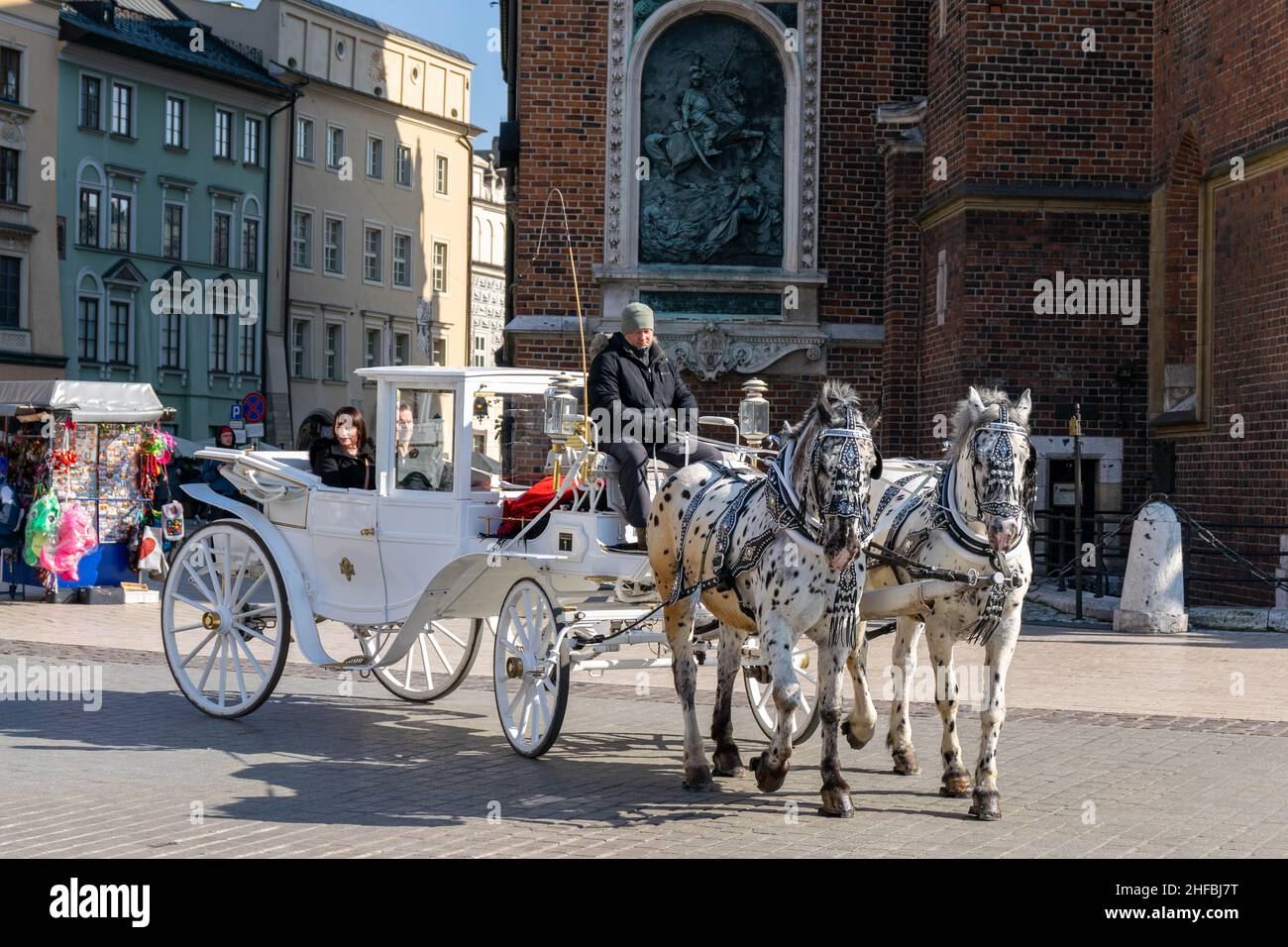 Cracovia, Polonia - 9th marzo 2020: I turisti si godono un giro a cavallo e in carrozza, un tour di un'ora intorno a Cracovia. Casa bianca e nera con l'uomo fuori Foto Stock