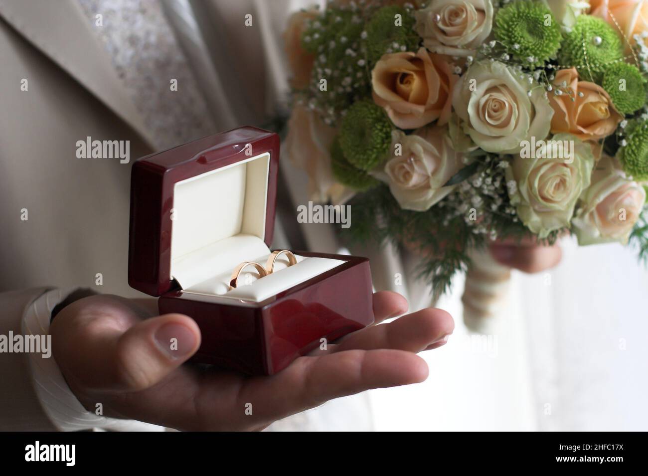 Lo sposo tiene la scatola degli anelli di nozze in una mano ed un bouquet nell'altra Foto Stock