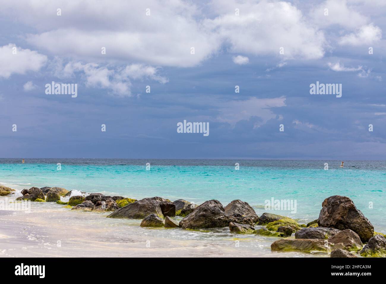 Le nuvole di tempesta fanno davvero risaltare le acque turchesi lungo questa spiaggia di Aruba Foto Stock