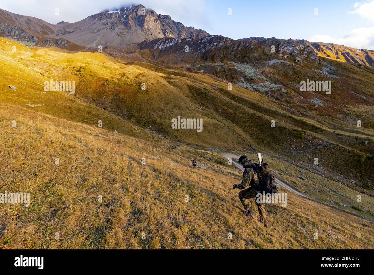 Un cacciatore che cammina sulle montagne svizzere al tramonto Foto Stock