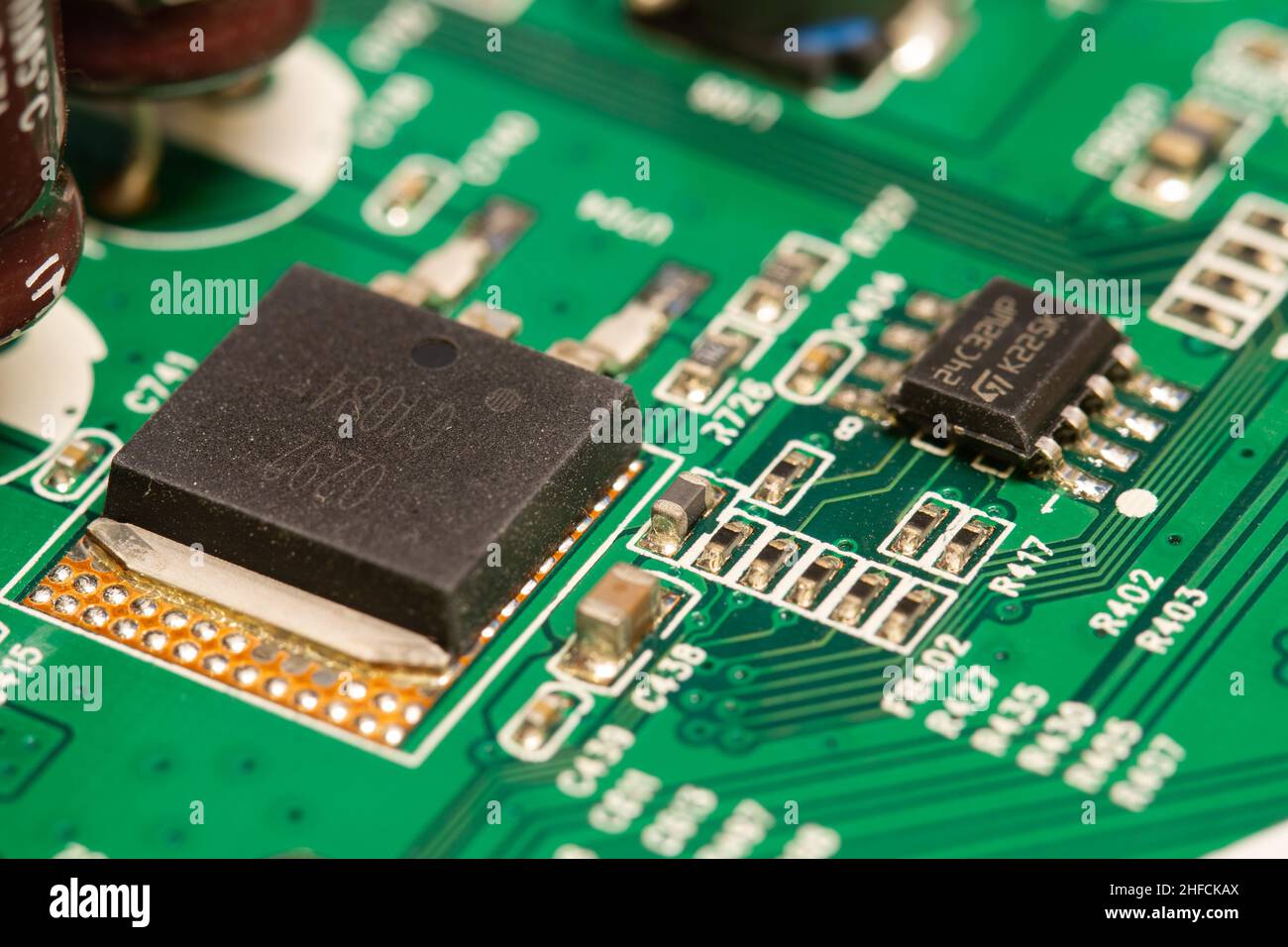 Molti piccoli componenti elettronici saldati su una scheda a circuito stampato (PCB) verde. Foto Stock