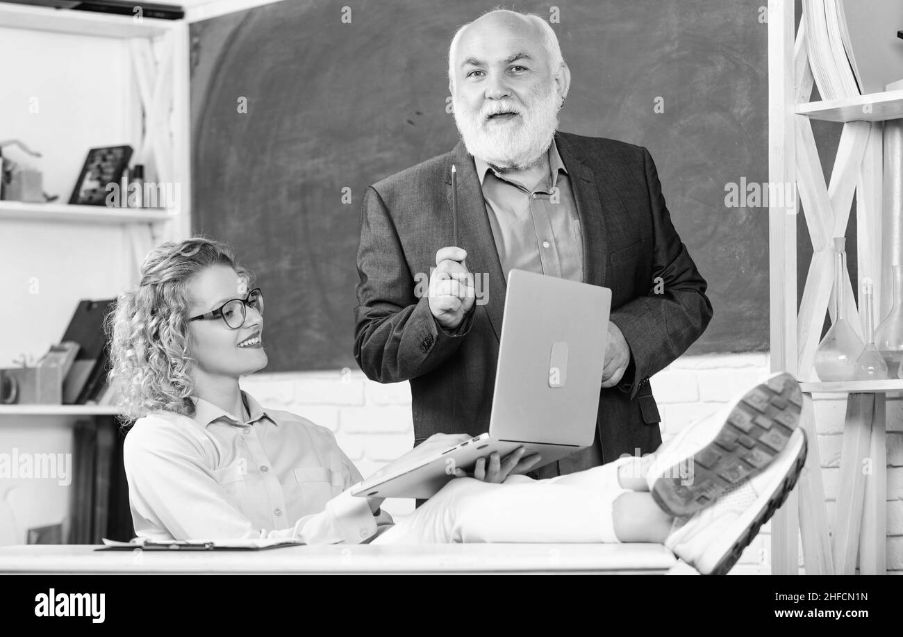 Lezione interessante. Insegnante e donna di livello superiore a scuola. Studente e tutor con laptop. Pass exam. Sala insegnanti. Scuola moderna. Felice Foto Stock