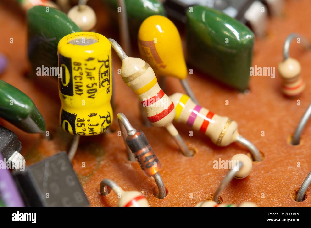 Vecchio circuito stampato con componenti elettronici come resistori e condensatori. Foto Stock