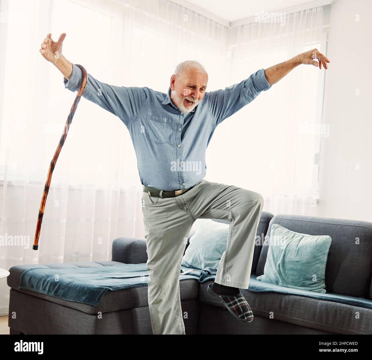Ritratto di un uomo anziano attivo con un bastone di canna che balla a casa Foto Stock