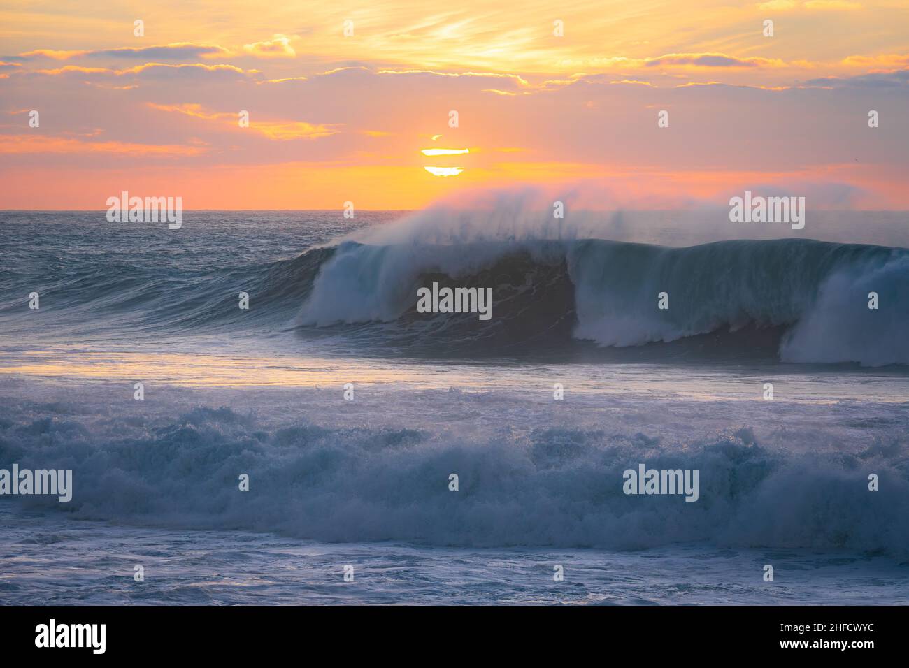 Le onde oceaniche si avvicinano al tramonto. Spiaggia di Guincho, Cascais, Portogallo Foto Stock