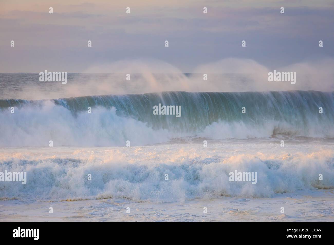 Le onde oceaniche si avvicinano al tramonto. Spiaggia di Guincho, Cascais, Portogallo Foto Stock