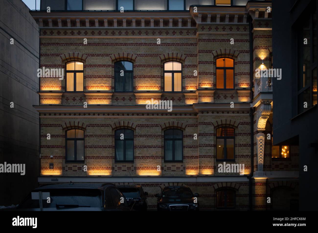 Riga, Lettonia, 4 gennaio 2022: Vista della città con illuminazione elettrica in finestre nel quartiere residenziale di Uptown Foto Stock