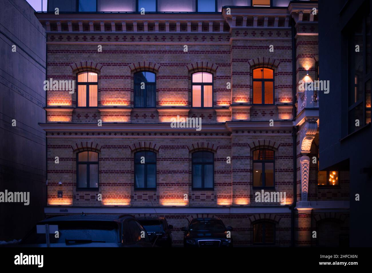Riga, Lettonia, 4 gennaio 2022: Vista della città con illuminazione elettrica in finestre nel quartiere residenziale di Uptown Foto Stock