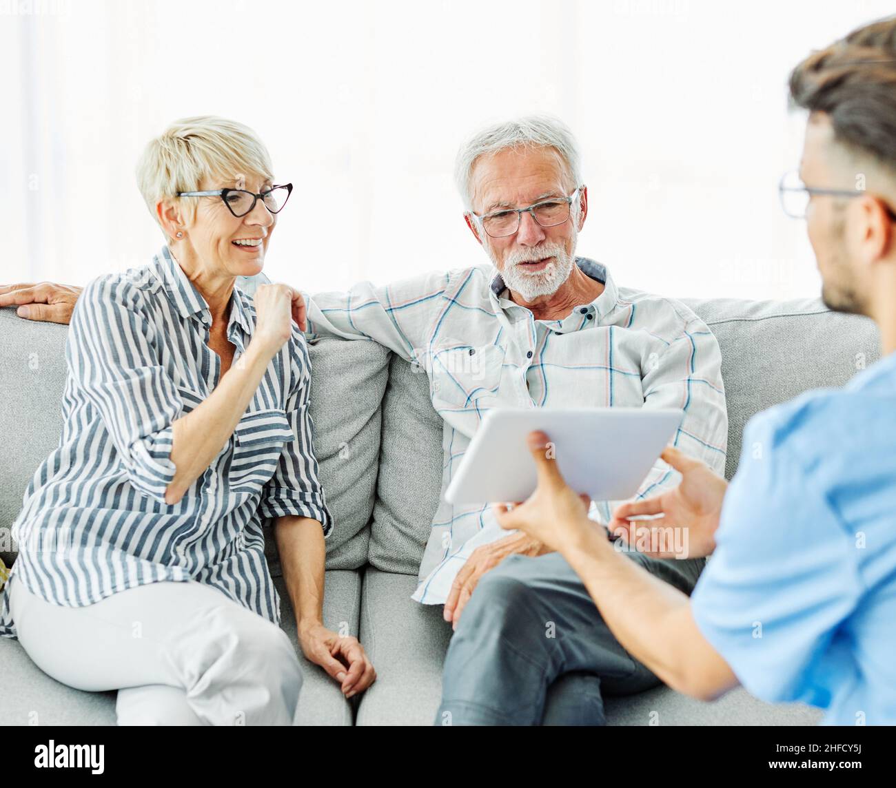 infermiera medico anziano cura di coppia caregiver aiuto pensione assistenza casa infermieristica anziano uomo donna tablet tecnologia Foto Stock