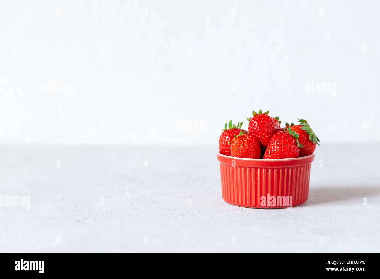 fragole fresche e luminose in un piccolo recipiente rosso, fuoco selettivo, spazio copia Foto Stock