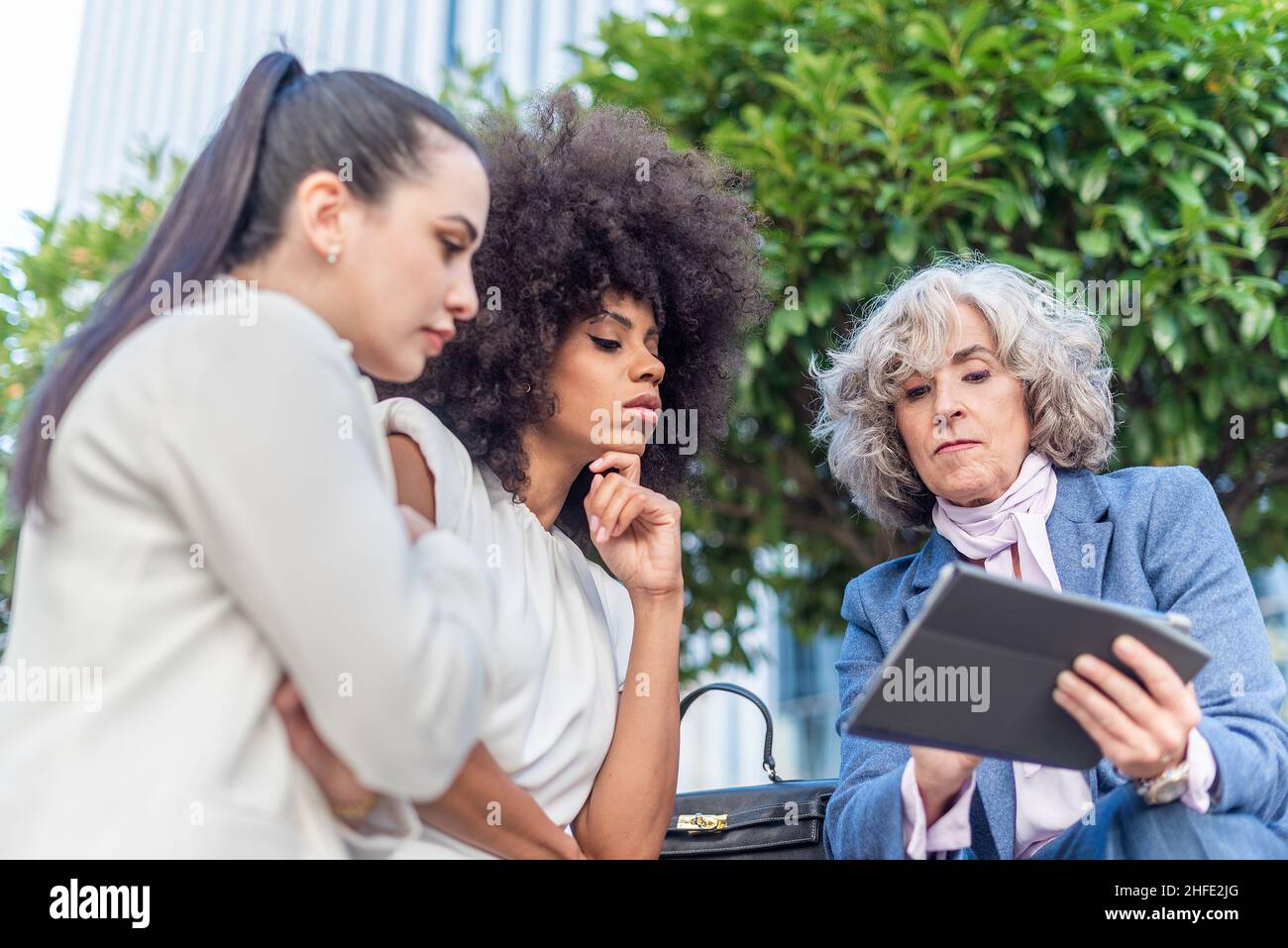 tre lavoratrici che studiano informazioni aziendali in città Foto Stock