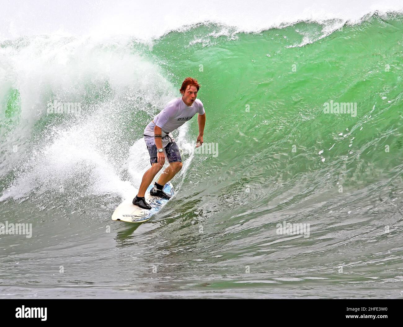 Un surfista caucasico che cavalca una grande onda all'Airport Reef di Tuban, Bali, Indonesia. Foto Stock