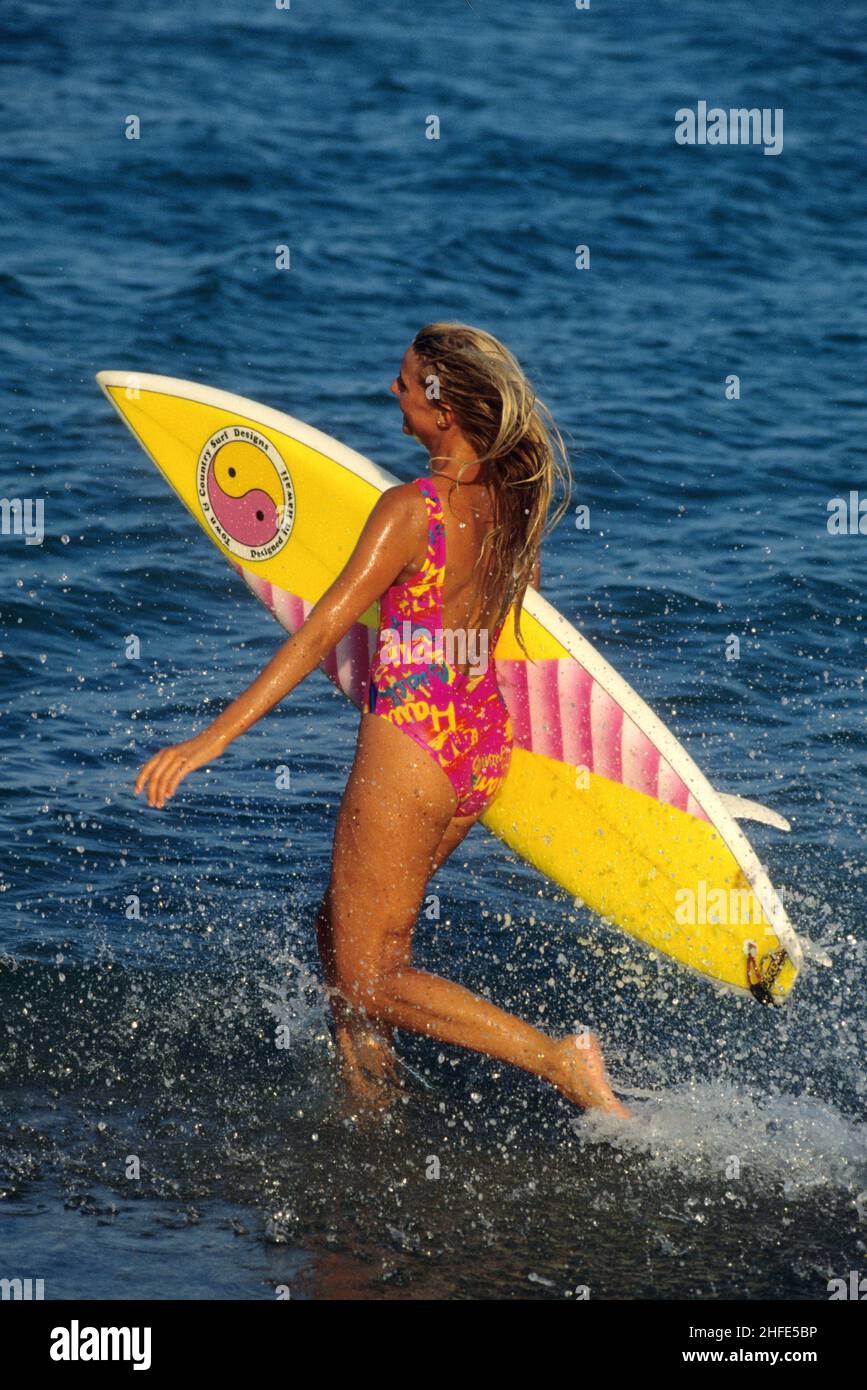 bellezza attraente capelli biondi silhouet sportivo con surf running sulla spiaggia spruzza uno sfondo di acqua di mare Foto Stock