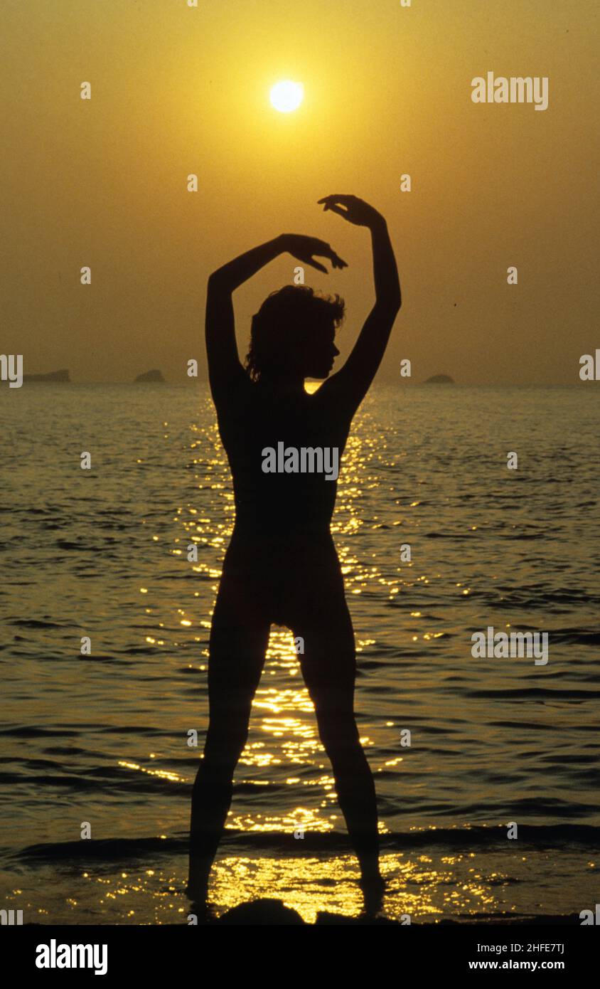 profilo donna silhouette guardando tramonto spiaggia estate evocazione calda luce del giorno sole riflessione sul mare Foto Stock