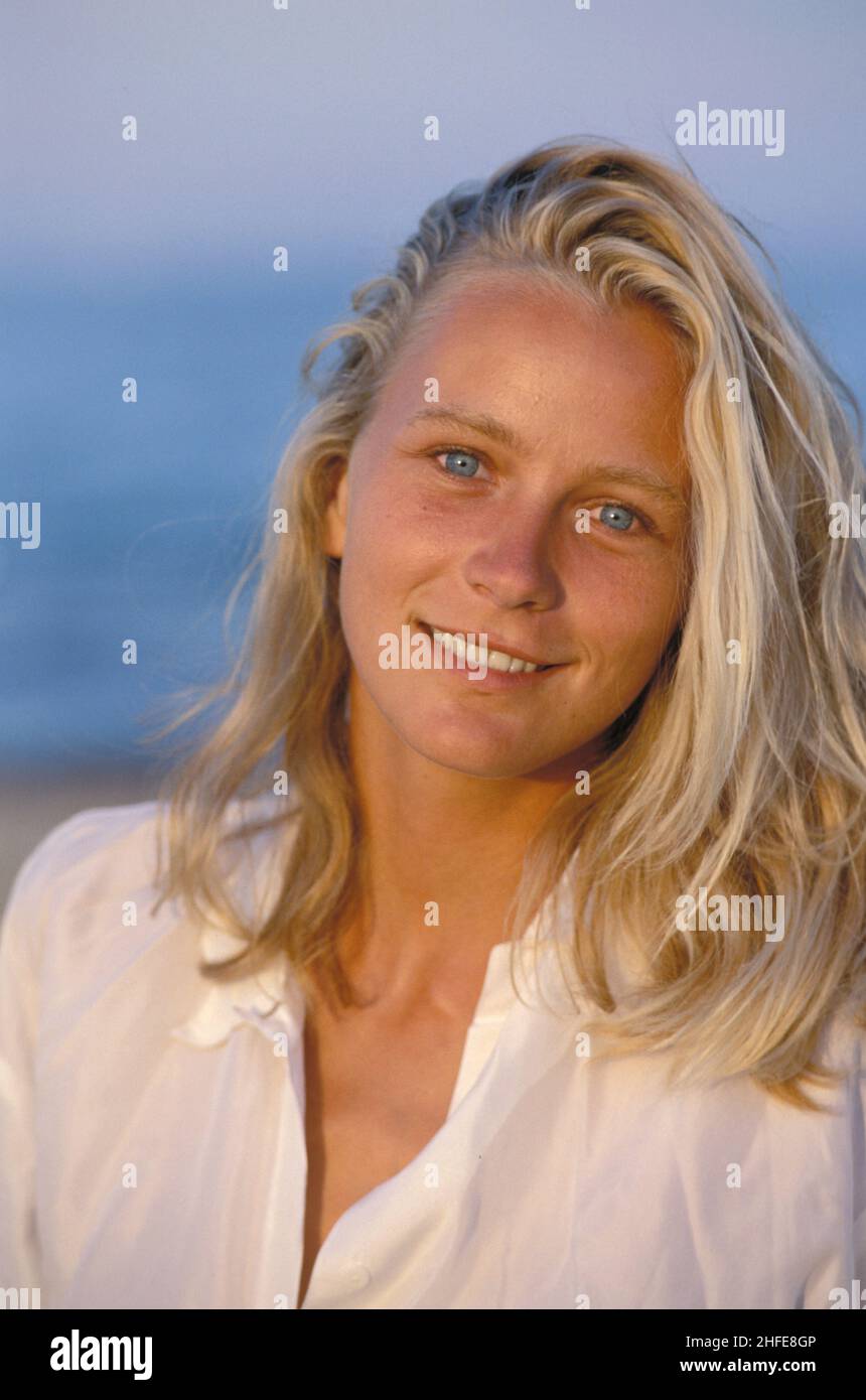 capelli biondi grazioso giovane donna vista ritratto naturale vista anteriore fotocamera blu sorridente blu cielo seawter sfondo Foto Stock