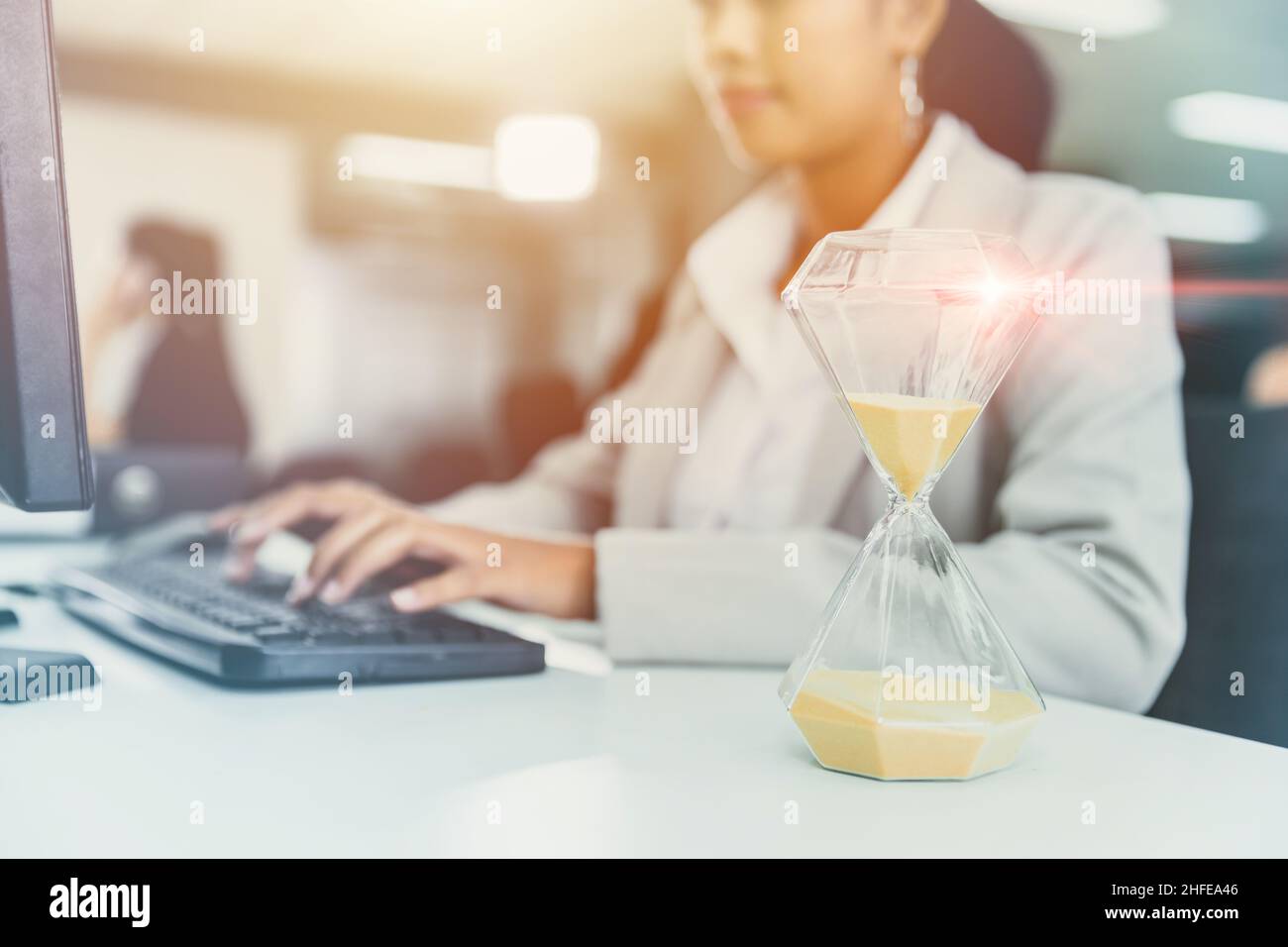 Business Woman gara di lavoro contro il tempo con Times Hourglass su scrivania Orologio per ufficio orario di lavoro concetto Foto Stock