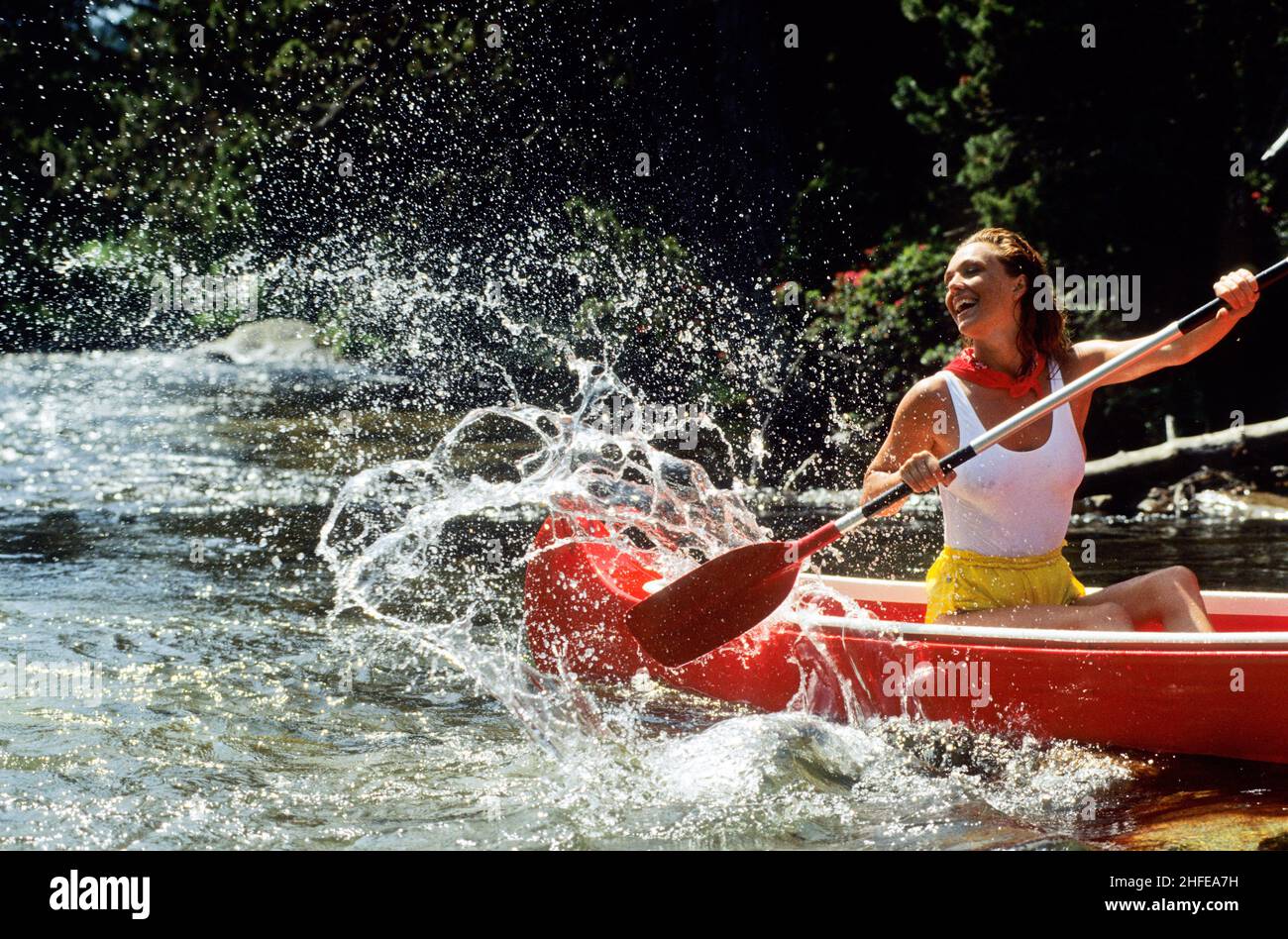 capelli biondi felice sorridente giovane donna canoo sul fiume montagna spalishing con pagaia Foto Stock