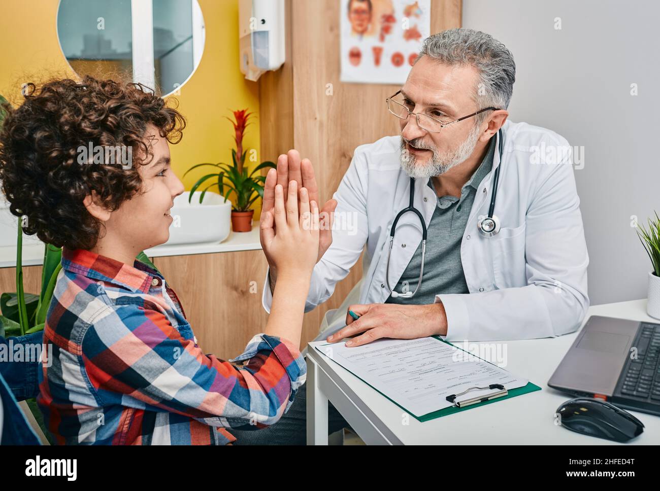 Pediatra amichevole divertirsi con il suo bambino paziente in ufficio medico e dà cinque per ragazzo. Consultazione pediatra, salute dei bambini Foto Stock