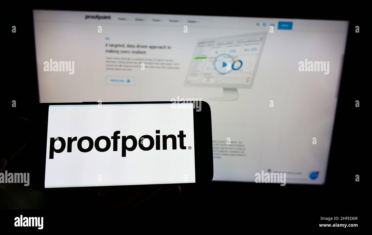 Persona che tiene lo smartphone con il logo della società statunitense di software di sicurezza Proofpoint Inc. Sullo schermo di fronte al sito Web. Mettere a fuoco sul display del telefono. Foto Stock