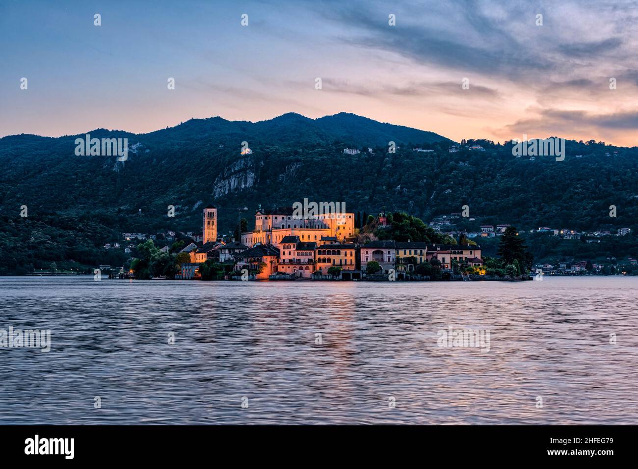 Isola di San Giulio con Basilica di San Giulio vista sul Lago d'Orta, montagne circostanti in lontananza, al tramonto. Foto Stock
