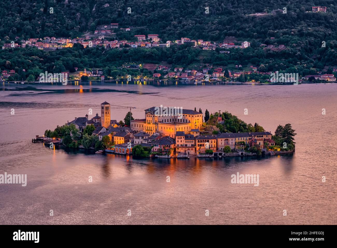 Veduta aerea dal Sacro Monte sull'Isola di San Giulio con la Basilica di San Giulio al centro del Lago d'Orta, illuminata di notte. Foto Stock