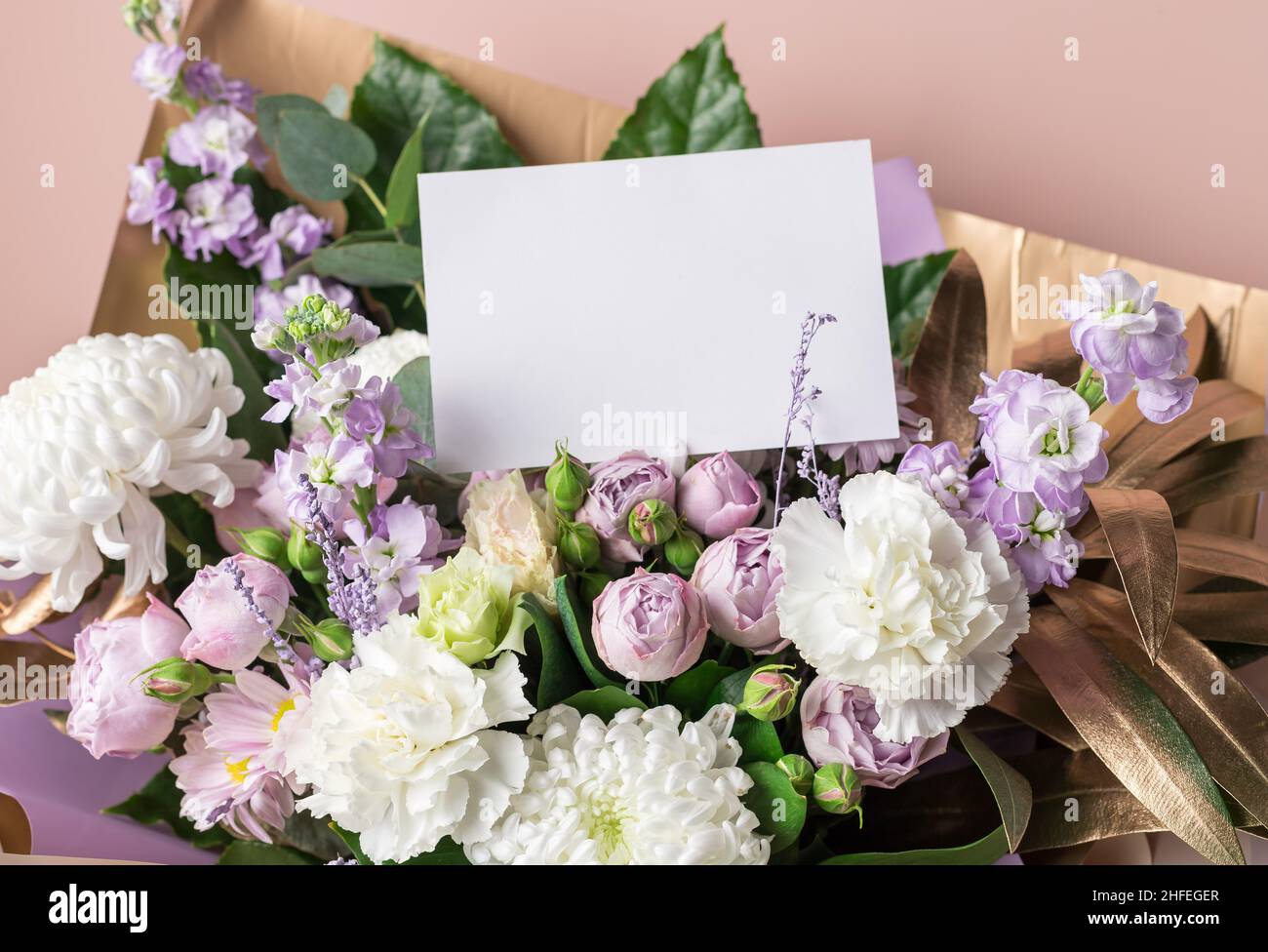 Composizione floreale decorativa con fiori misti, foglie dorate, carta bianca Foto Stock